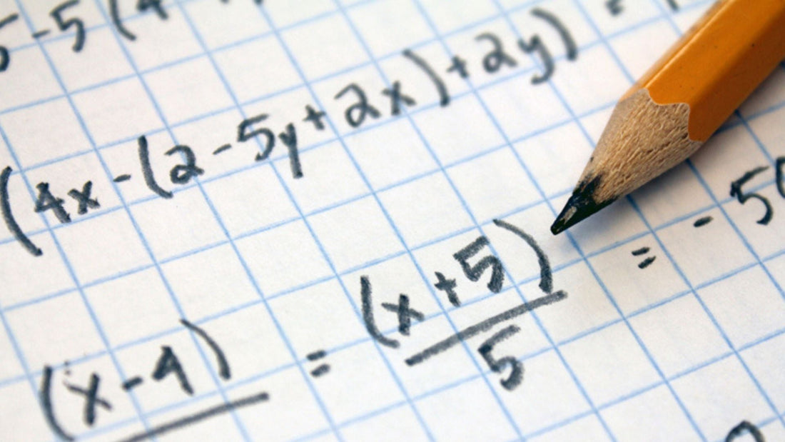 Handwritten algebra working on squared paper with a pencil resting on it